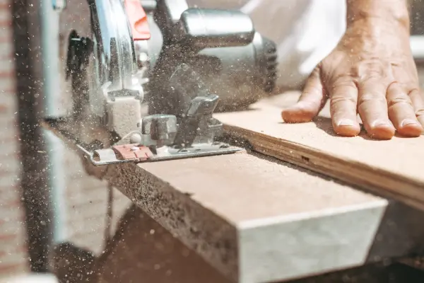 Photo of a man cutting a chipboard with a circular saw.